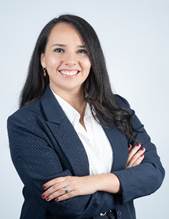 A person with long hair wearing a suit jacket  Description automatically generated